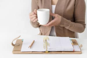 Woman holding coffee with planner