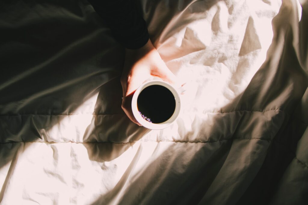 Woman holding coffee cup in bed