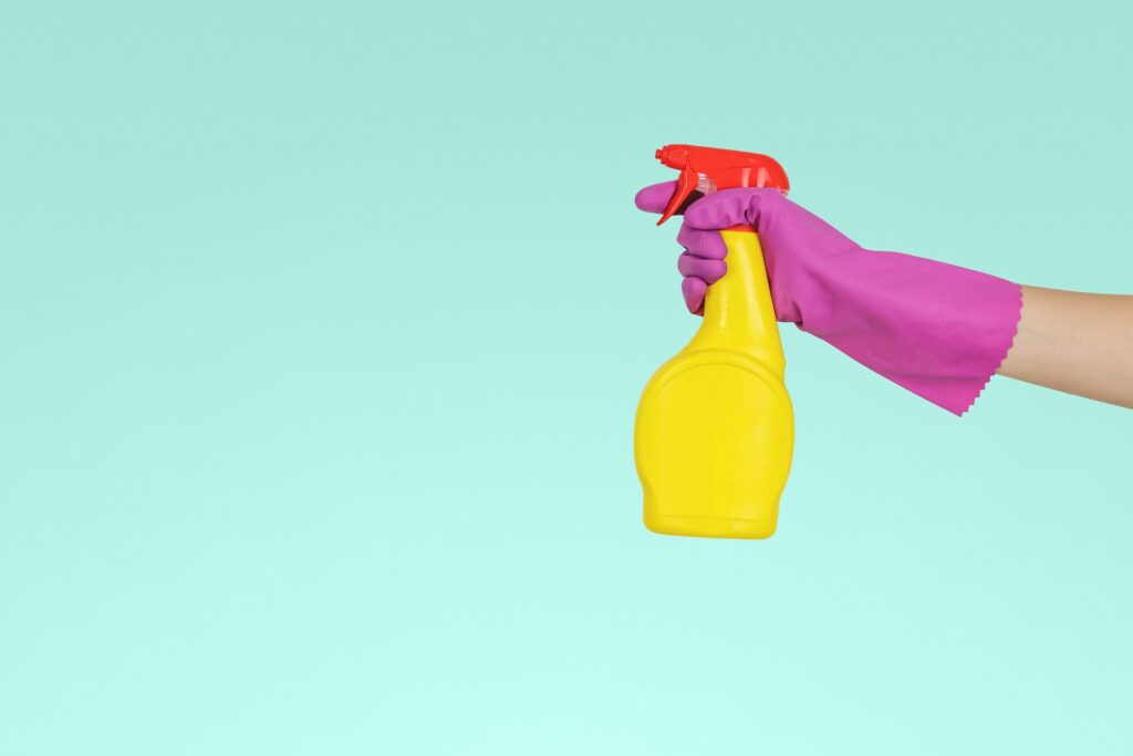 Woman in rubber gloves holding spray bottle