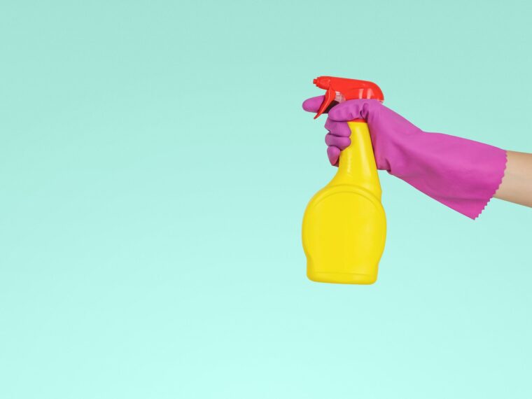 Woman in rubber gloves holding spray bottle