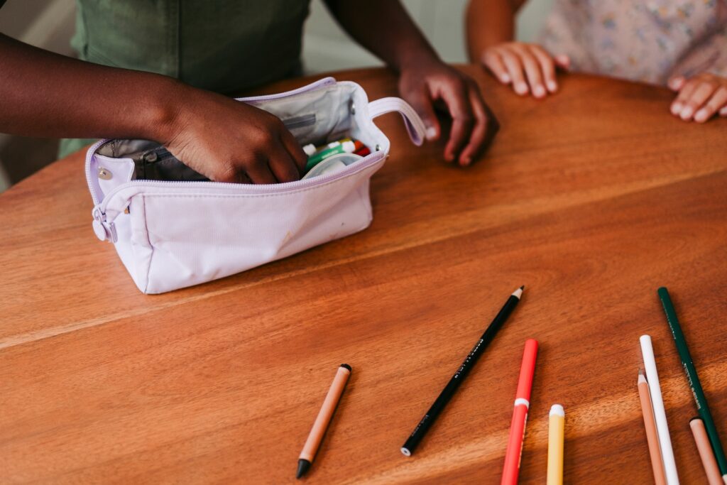 Girl getting school supplies from pencil case.