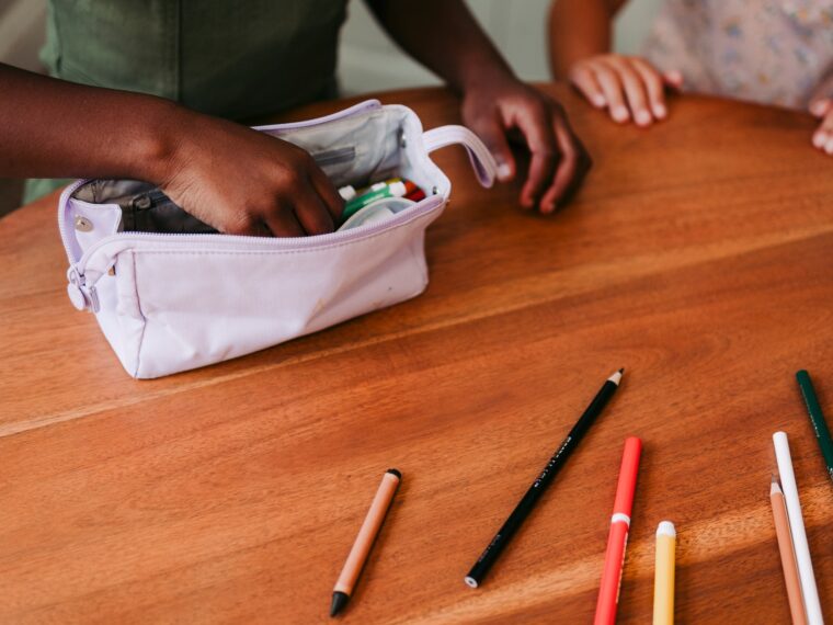 Girl getting school supplies from pencil case.