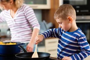 Boy helping mom with cooking dinner.